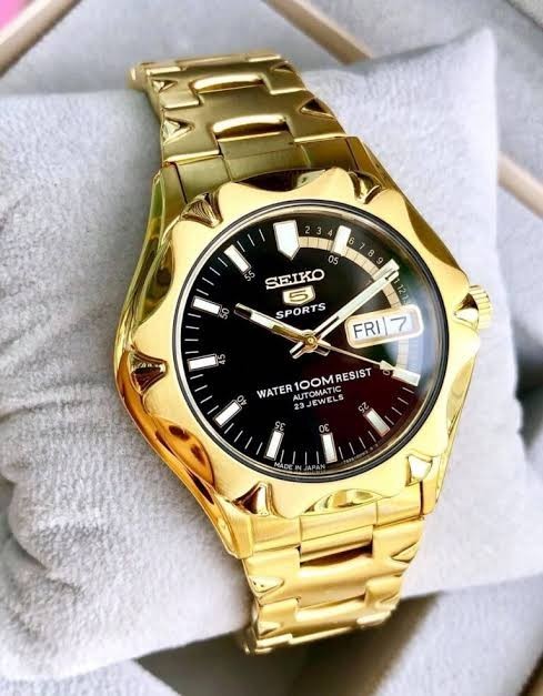 Digi Bear Seiko 5 Sports automatic watch with a gold-tone stainless steel case and black dial on a display cushion.