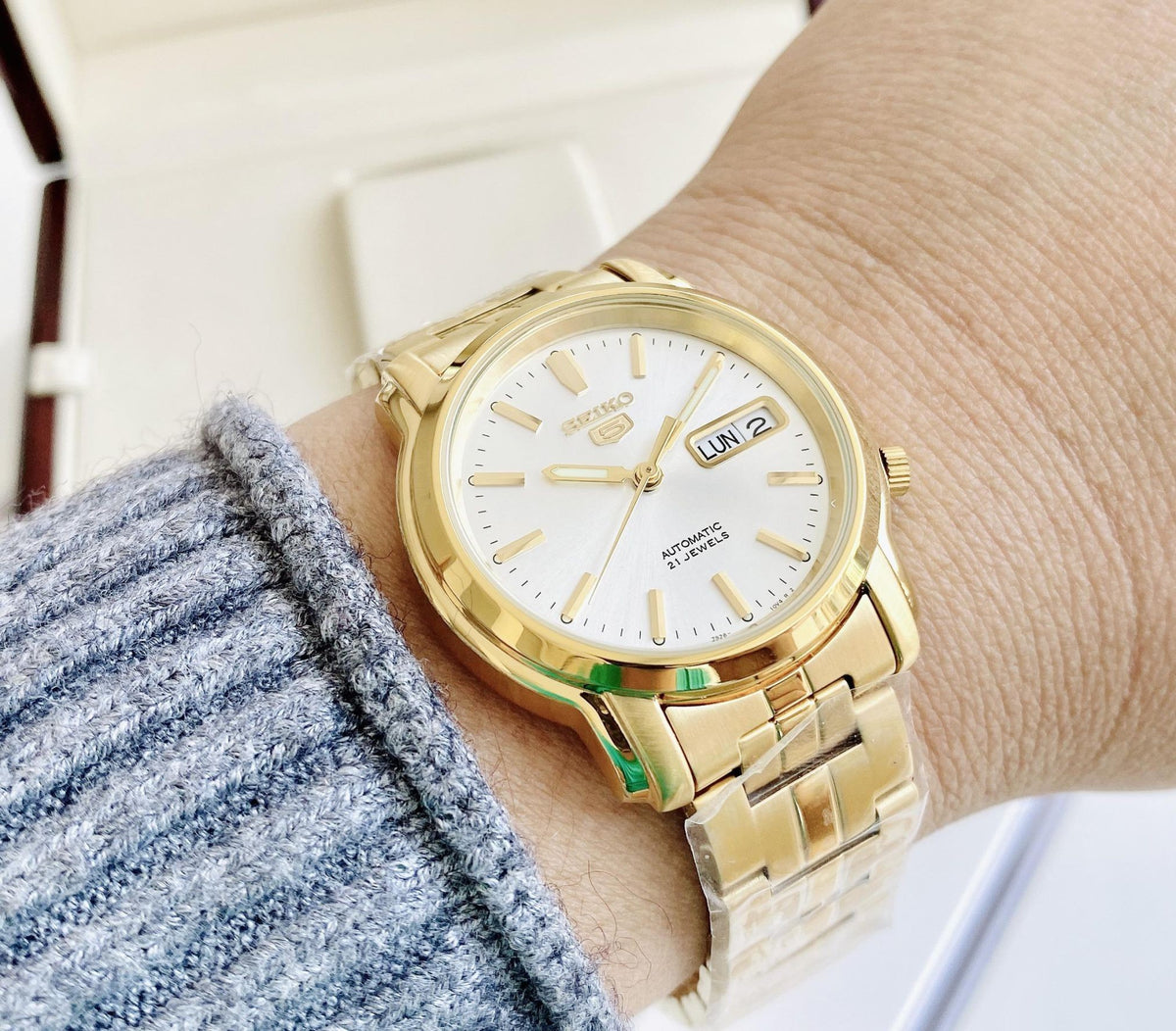 Digi Bear Seiko 5 SNKK74K1 automatic watch with a gold-tone stainless steel band and a white dial on a wrist